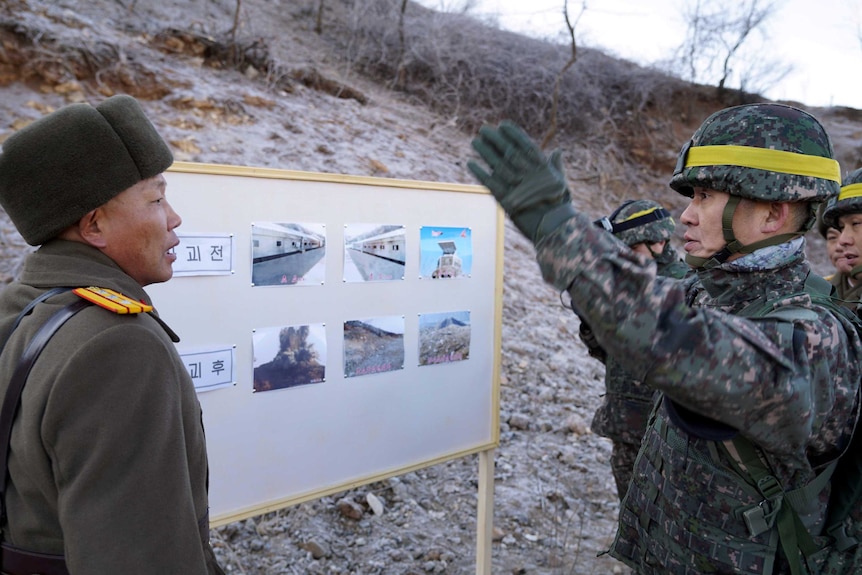 A South Korean soldier speaks and gestures to a North Korean soldier at the DMZ.