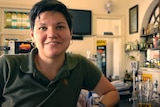 A woman with brown hair and a green shirt in a country pub.