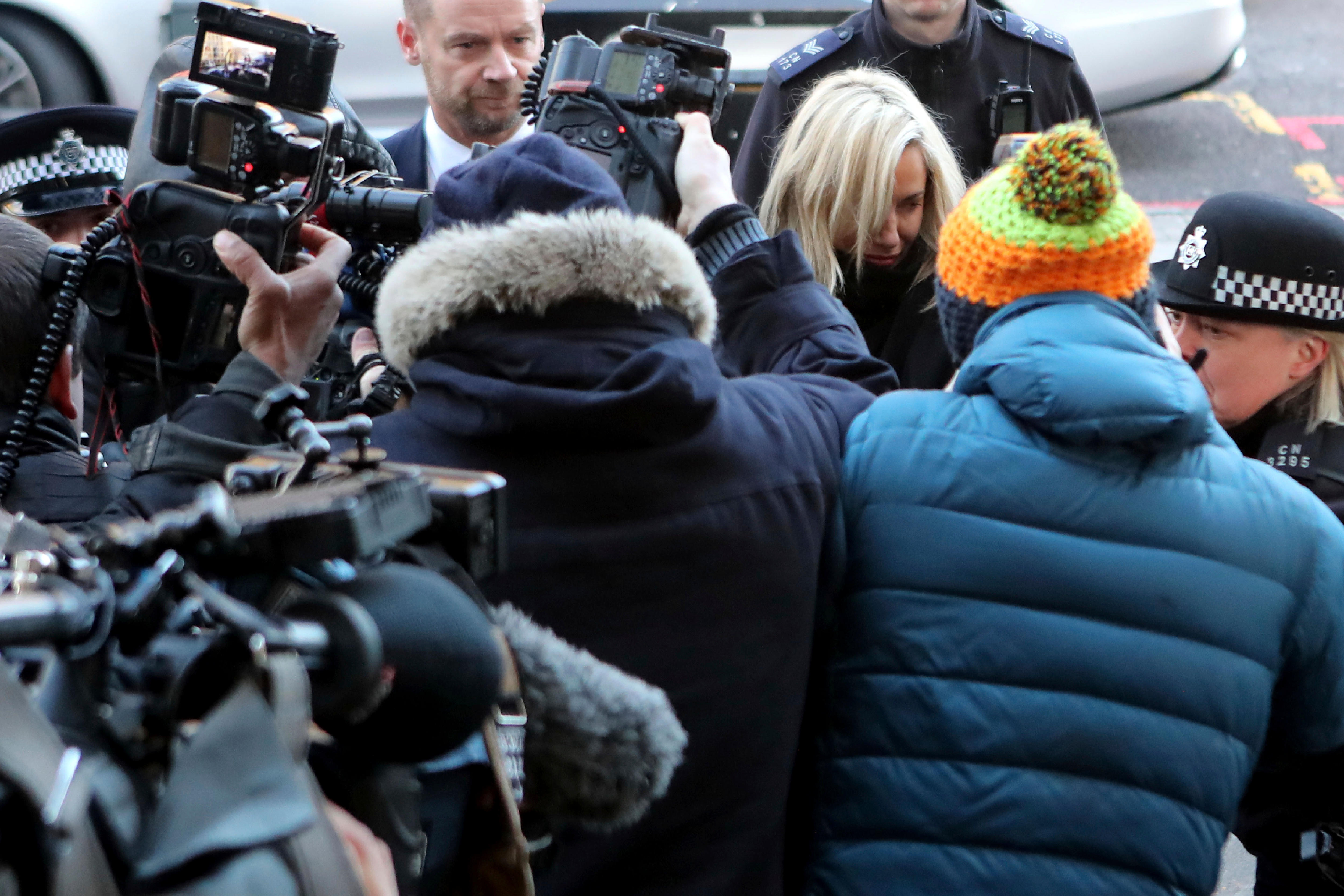 Flack is swarmed by papparazzi outside court. 