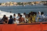 Rescued migrants arrive onboard a coastguard vessel at the harbour of Lampedusa on October 3, 2013