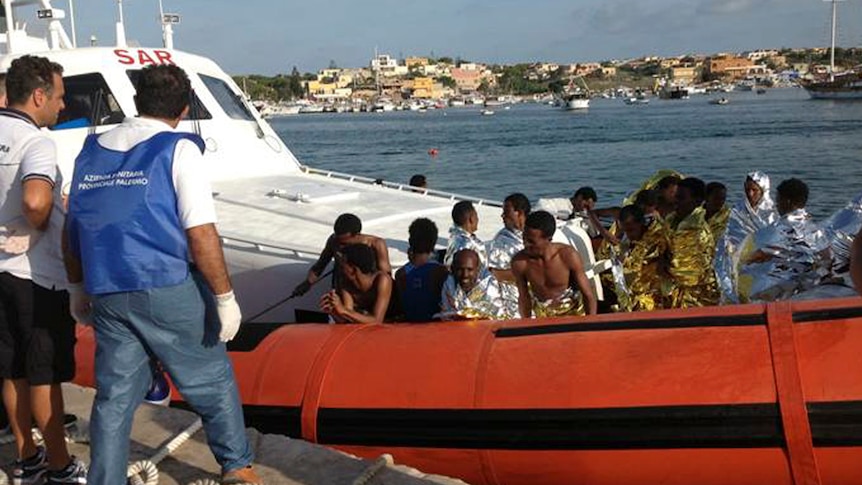 Rescued migrants arrive onboard a coastguard vessel at the harbour of Lampedusa on October 3, 2013
