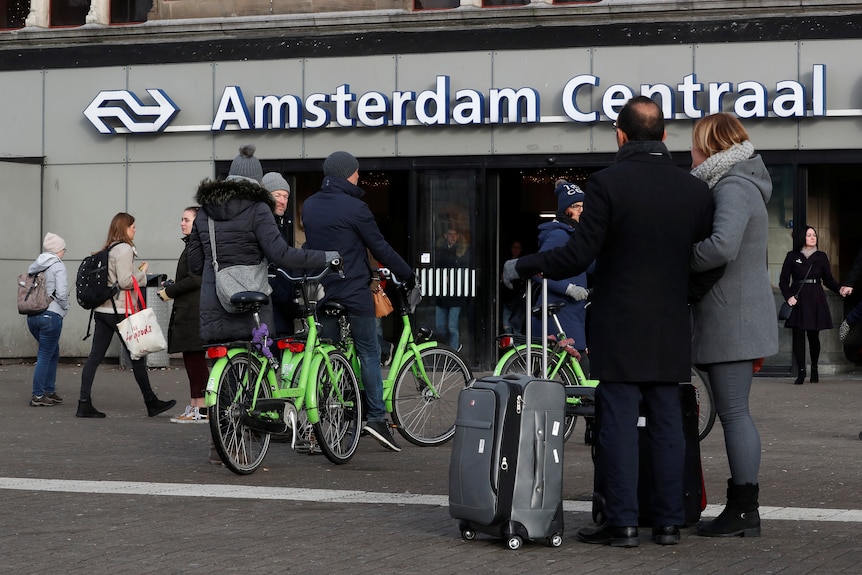 People grab bicycles outside a train station in Amsterdam. 