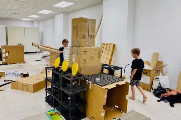 Kids building a castle out of cardboard boxes.