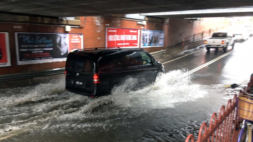 A van driving through a flooded underpass on Victoria St at Footscray.