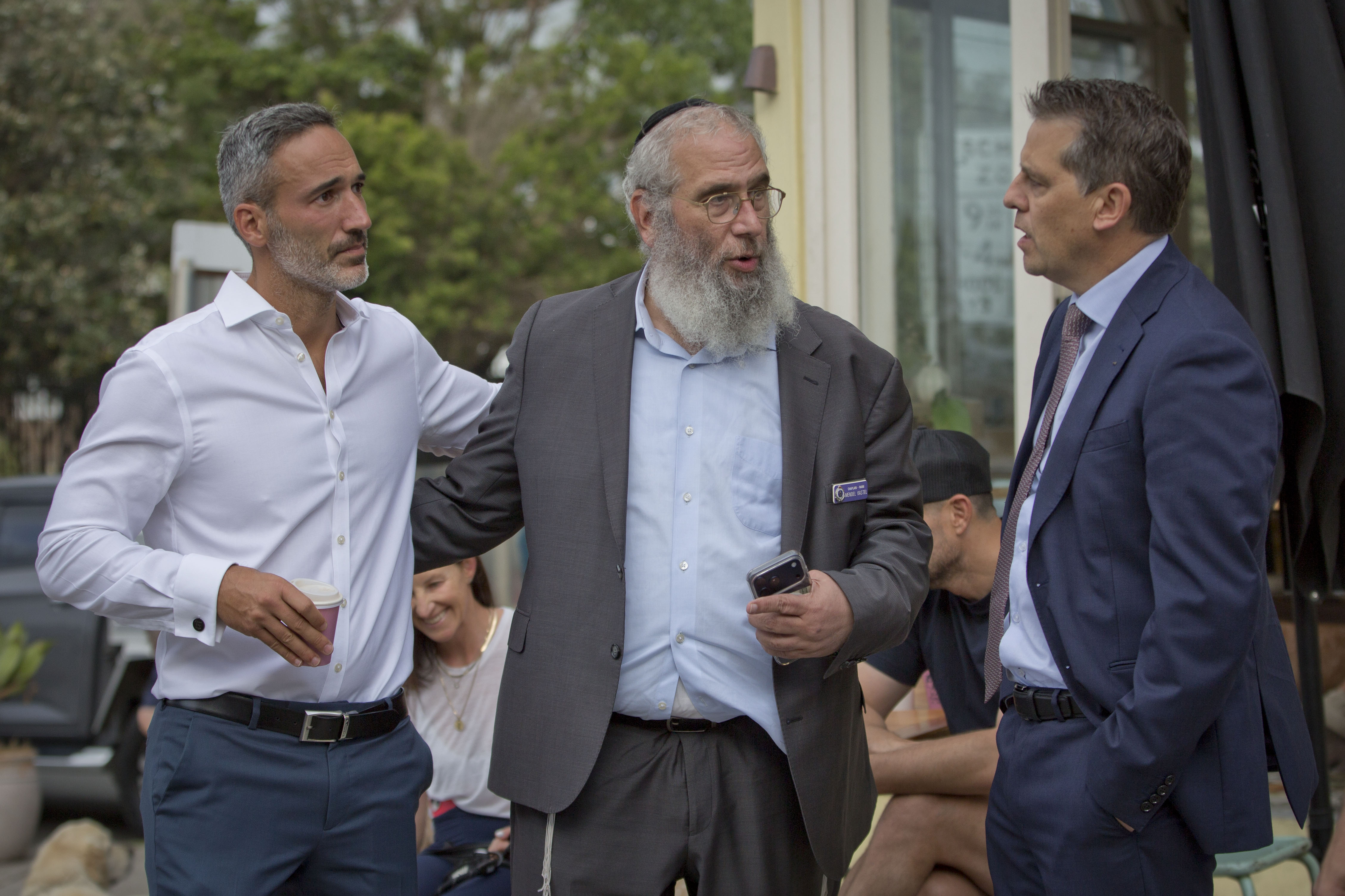 Três homens de terno conversando entre si