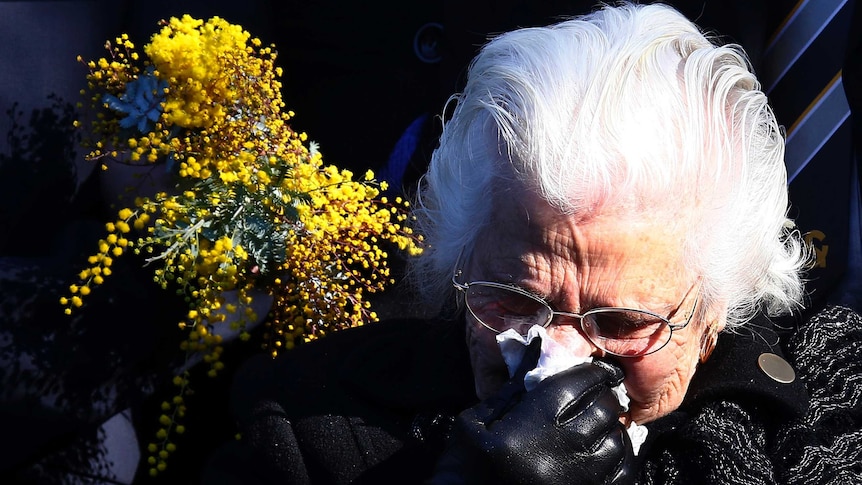 Relative of MH17 victim cries while placing floral tribute at memorial