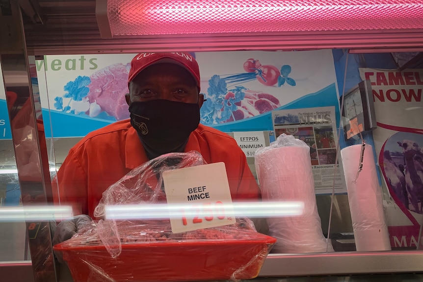 Man holding beef mince meat at butcher shop.