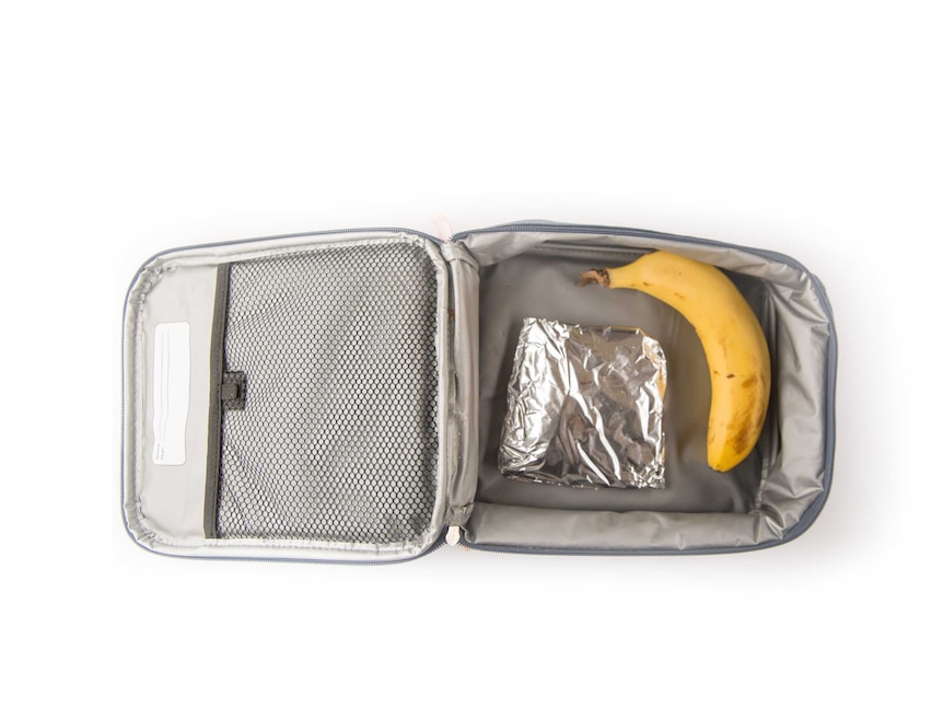 A cheese and tuna sandwich wrapped in foil and a banana in a grey cooler bag.