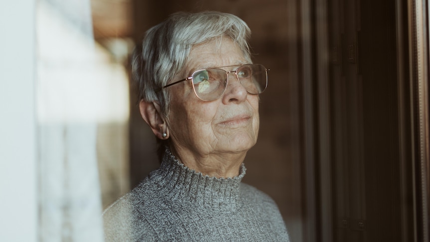 Elderly woman looking out of a window 