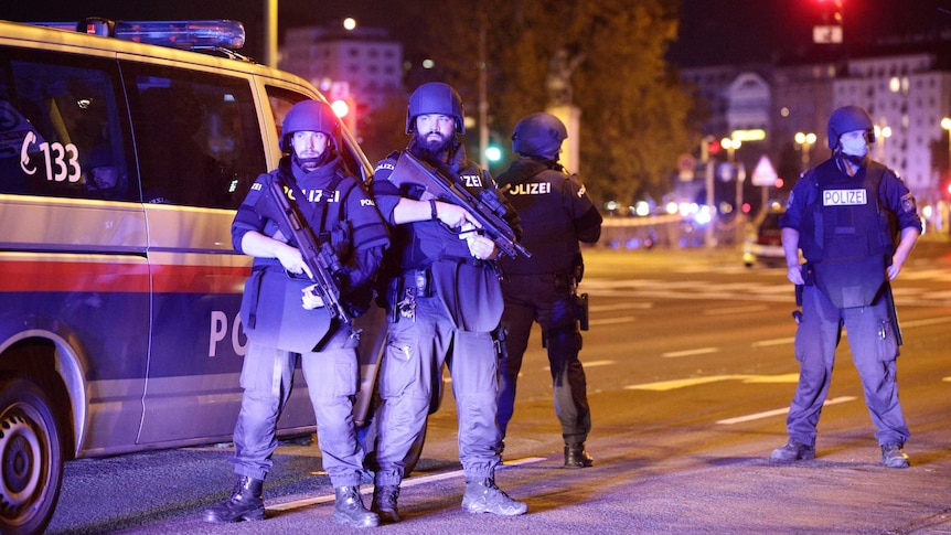 Four armed police officer in front of a police van in Vienna at night.