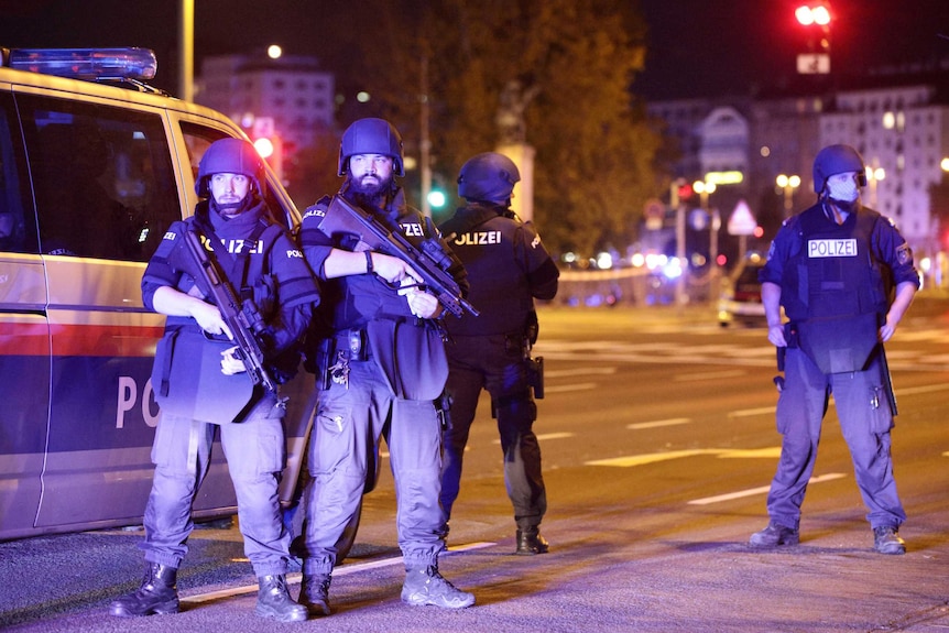 Four armed police officer in front of a police van in Vienna at night.