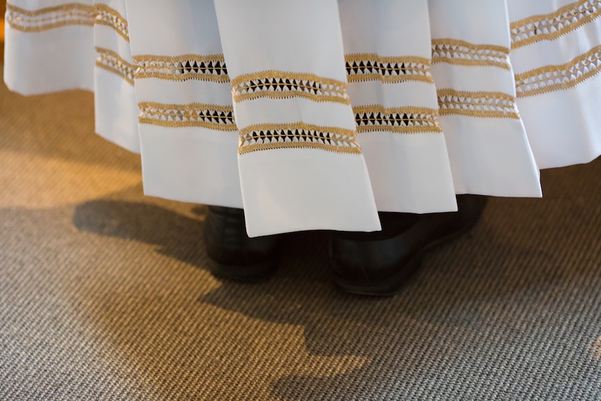 The crisp pleats and embroidered details on the hem of a priest's robes.