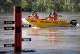 A State Emergency Service (SES) crew motors past a flood gauge on the swollen Balonne river in St George.