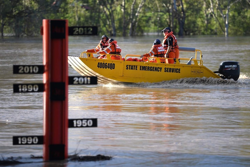 Une équipe du Service d'urgence de l'État (SES) passe devant une jauge d'inondation sur la rivière Balonne gonflée à St George.