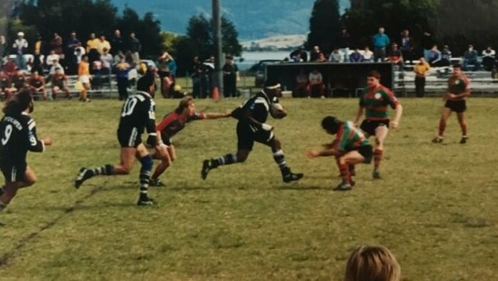 An old photo showing a Crookhaven Magpie player running the ball in a rugby league game against against Jambaroo at Warilla