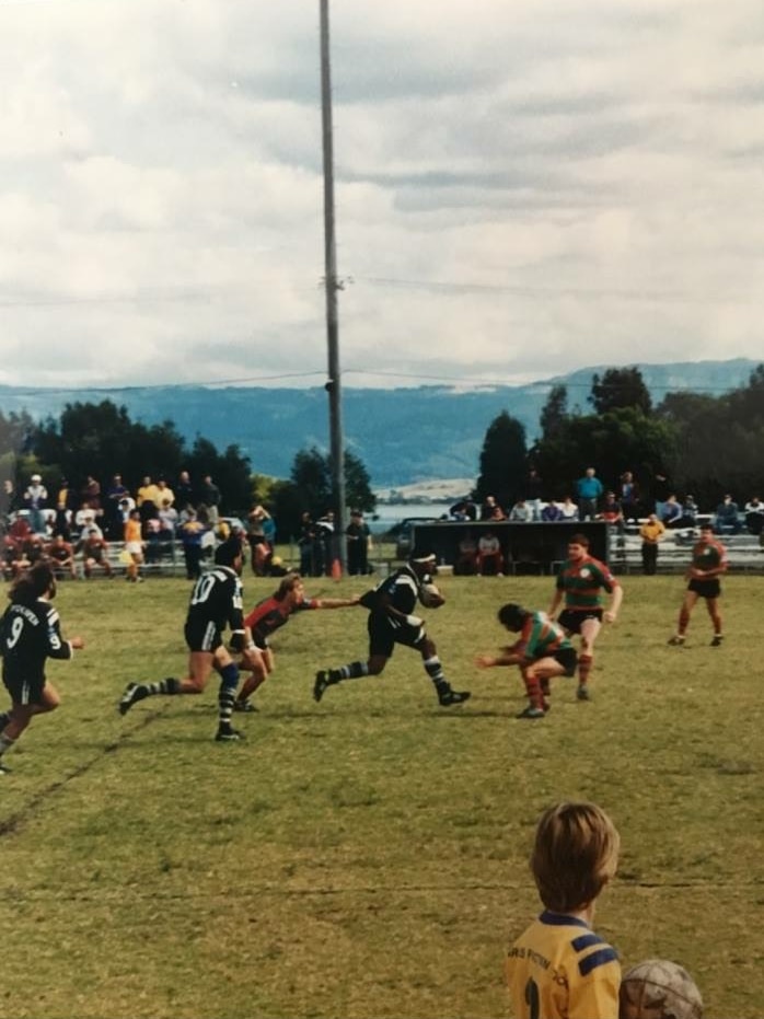 An old photo showing a Crookhaven Magpie player running the ball in a rugby league game against against Jambaroo at Warilla
