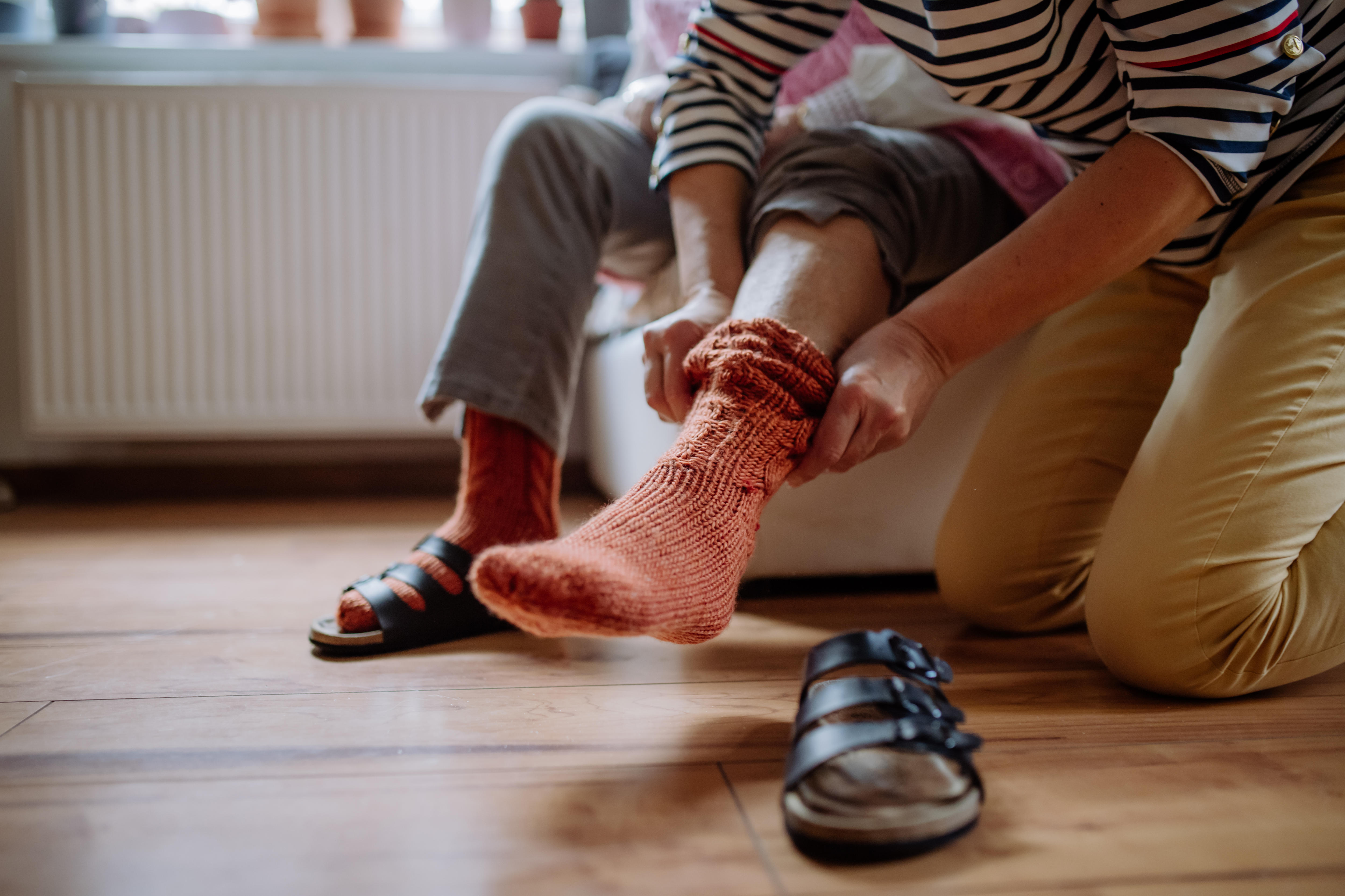 A woman assisting an elderly lady with putting on her socks