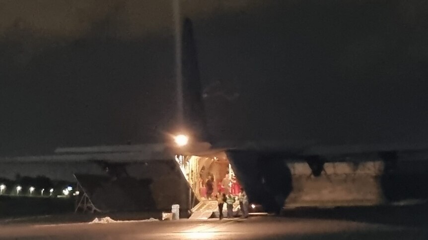 A plane is shown at night, evacuating passengers. 