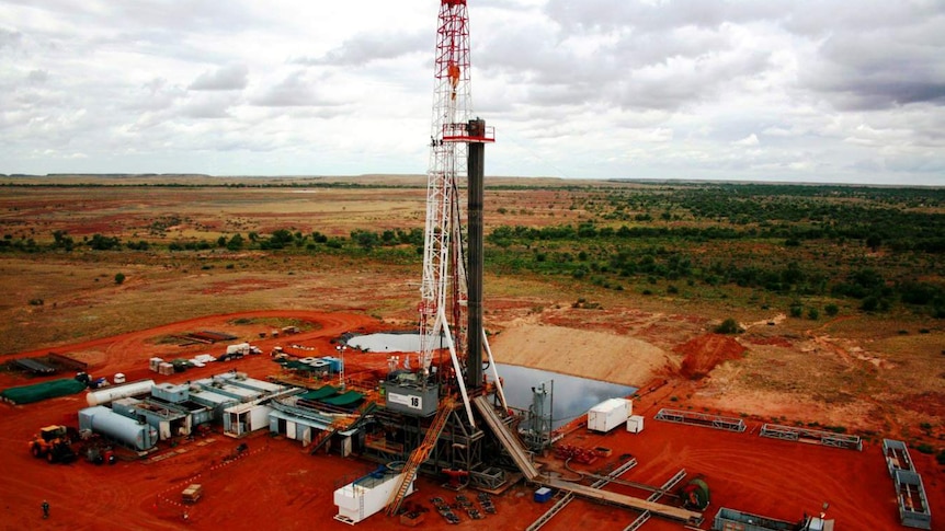 A tall piece of mining equipment with red dust surrounding it.