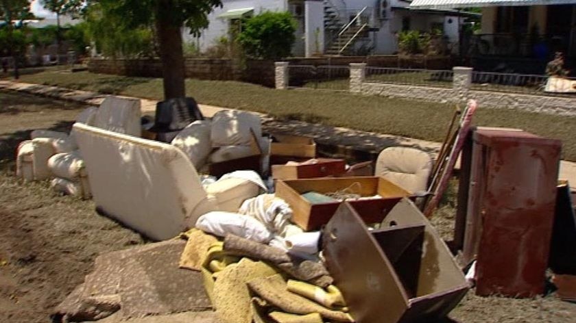 Clean-up: muddy, broken furniture and possessions in street outside houses in Ingham.