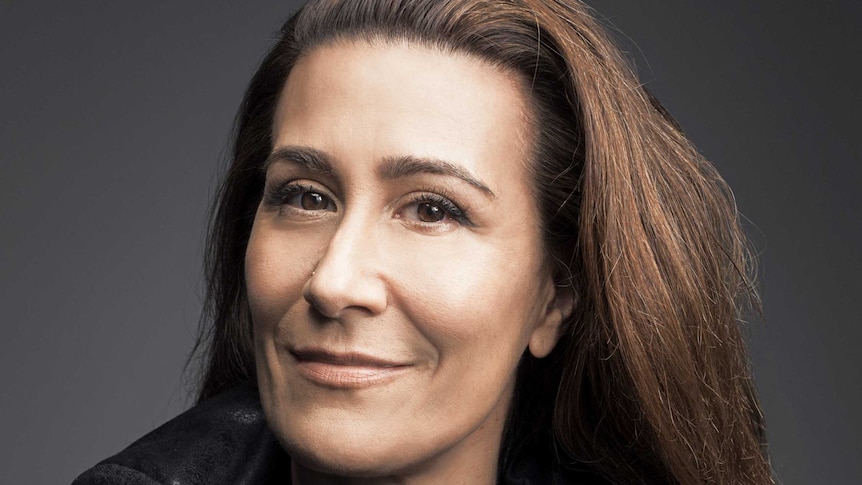 A headshot of Jeanine Tesori in front of a grey backdrop.