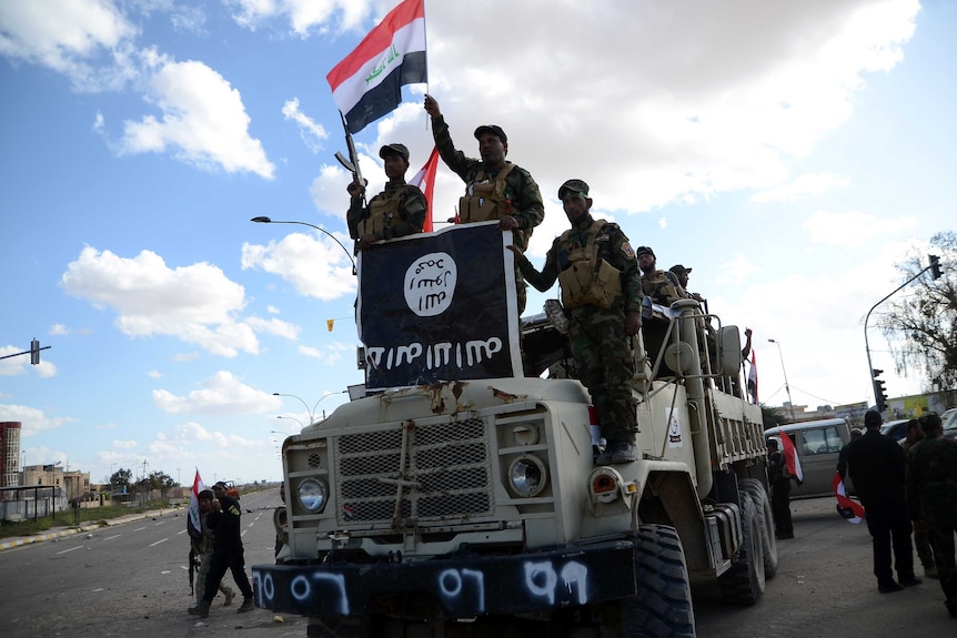 Shiite fighters celebrate on a truck seized from Islamic State militants in Tikrit