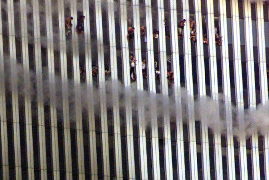 As smoke drifts past, people look out the windows of the World Trade Centre's north tower