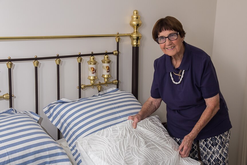 Parkes Elvis Festival home host Kath Hutchison makes a bed in her home as she prepares for guests