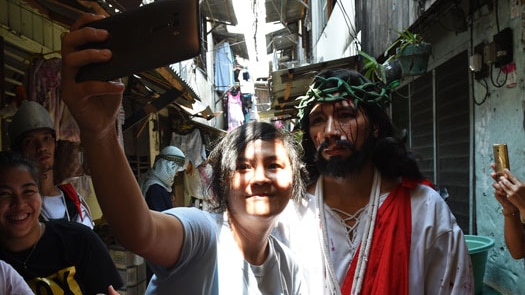 A spectator takes a selfie with an actor playing the role of Jesus
