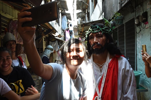 A spectator takes a selfie with an actor playing the role of Jesus