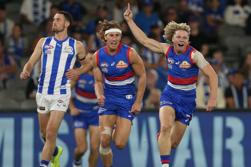 Cody Weightman holds his hand up and smiles while Aaron Naughton chases after him