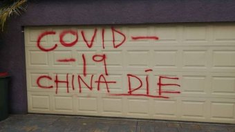 A garage door spray painted with the words Covid-19 China die".