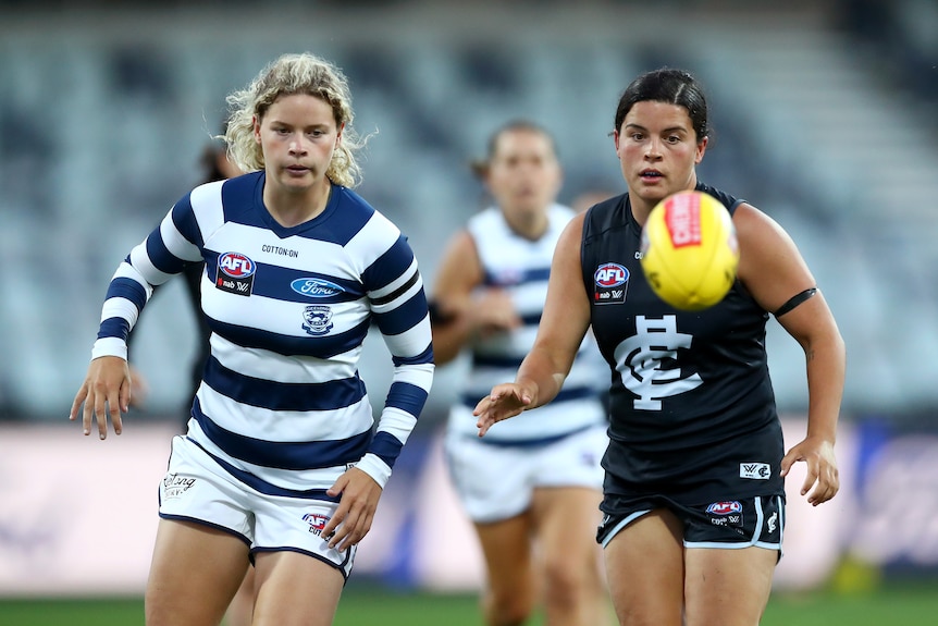 Two female AFLW players running for the yellow ball.