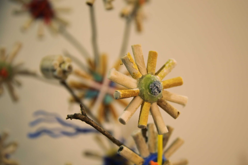 A sculpture of flowers constructed with old cigarette butts.