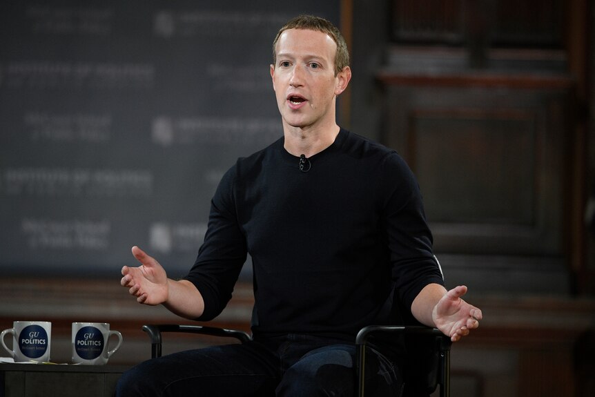 Mark Zuckerberg gesturing while wearing a black shirt and mic.