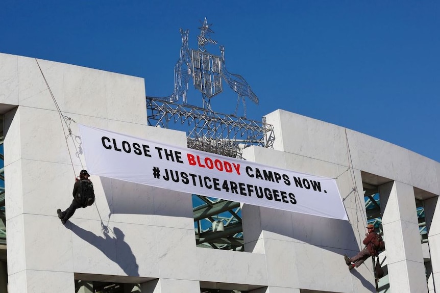 Protesters unfurl banners on front of Parliament house