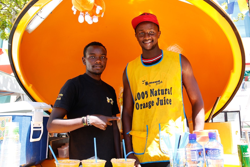 Two men stand inside a stall shaped like a giant orange.