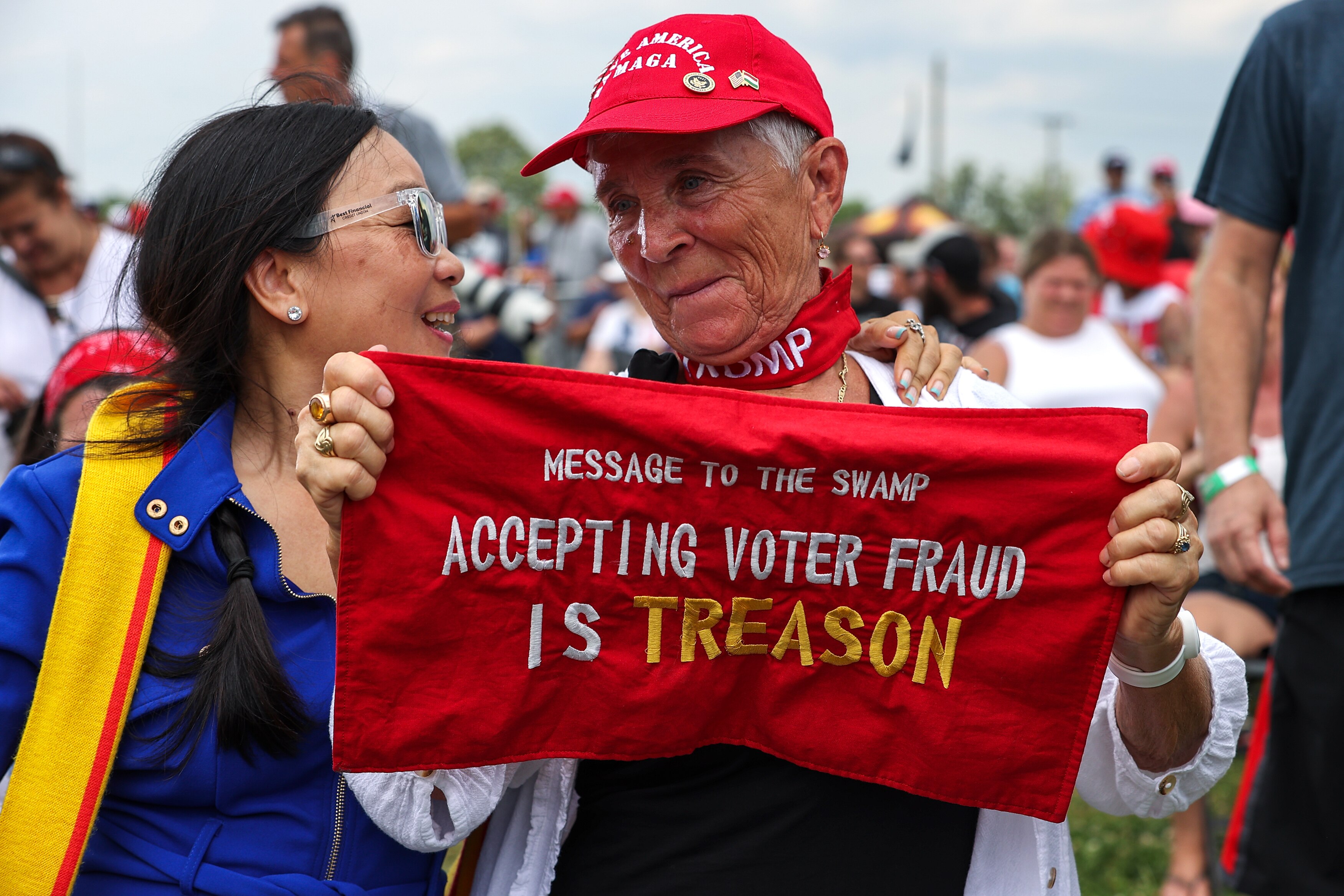 An elderly Trump supporter holds a sign that says 'Message to the swamp. Accepting voter fraud is treason'.