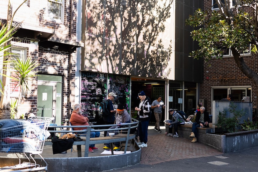 People mill about outside a brick building