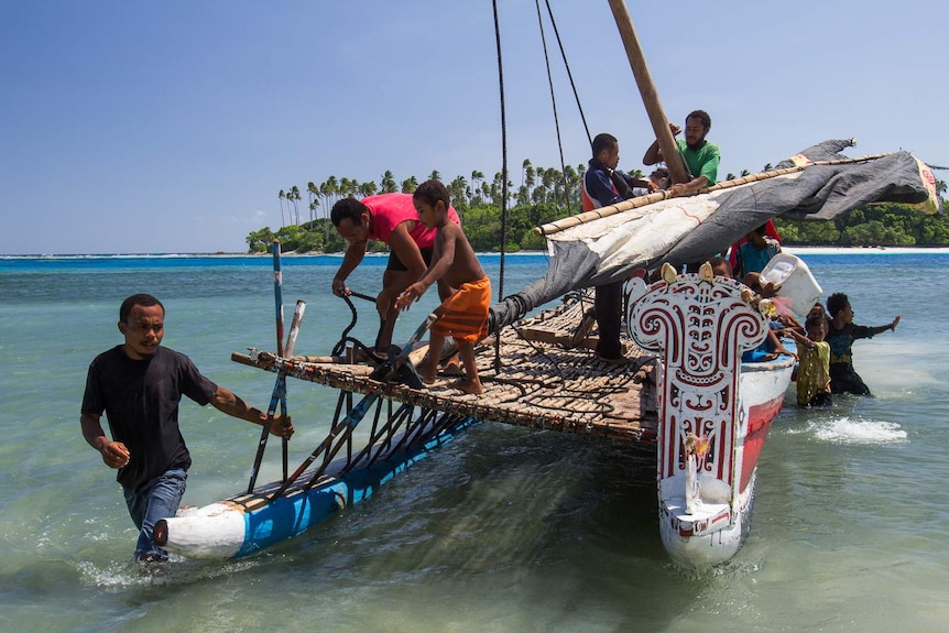 Men and children disembark from a nagega sailing canoe.