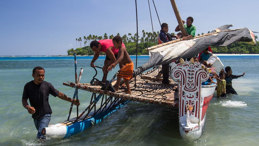 Men and children disembark from a nagega sailing canoe.