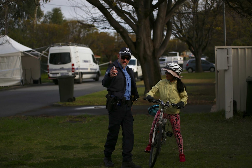 A police officer speaks with a woman on a bike.