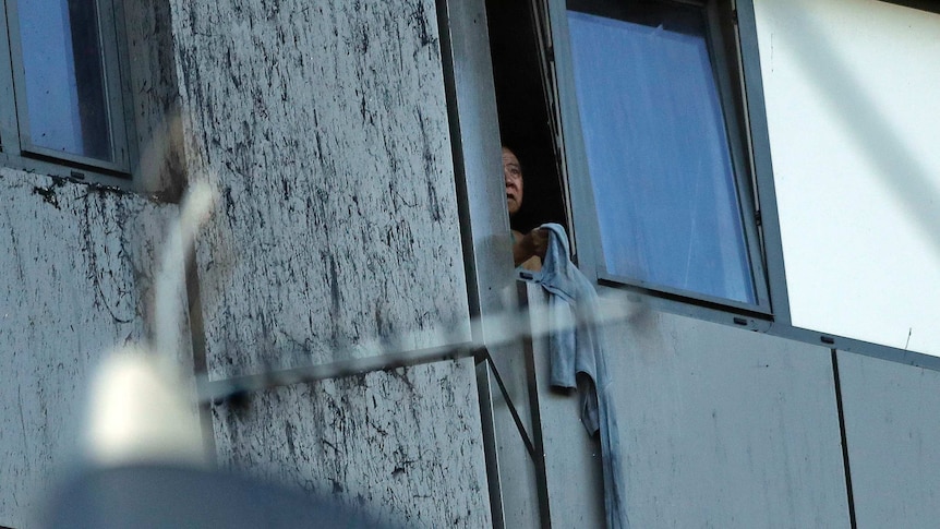 A person peers out of a window from burning Grenfell Tower