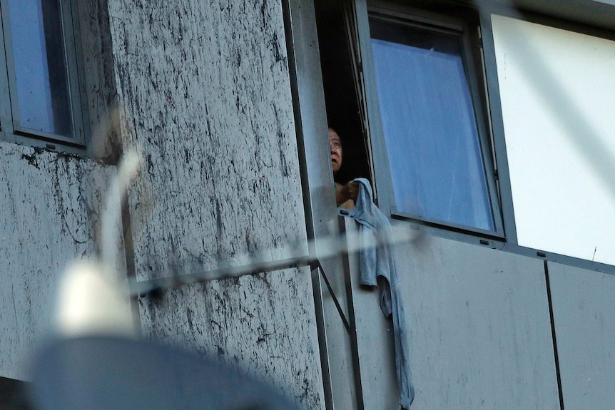 A person peers out of a window from burning Grenfell Tower