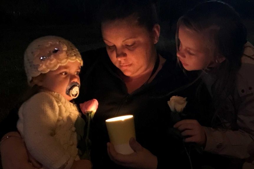 Mother Deanne Pokarier holds a candle with her two children at a vigil in Nambour.