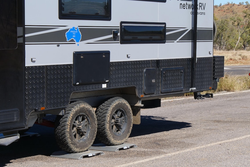 The rear end of a caravan with its wheels sitting on small metal square weight plates