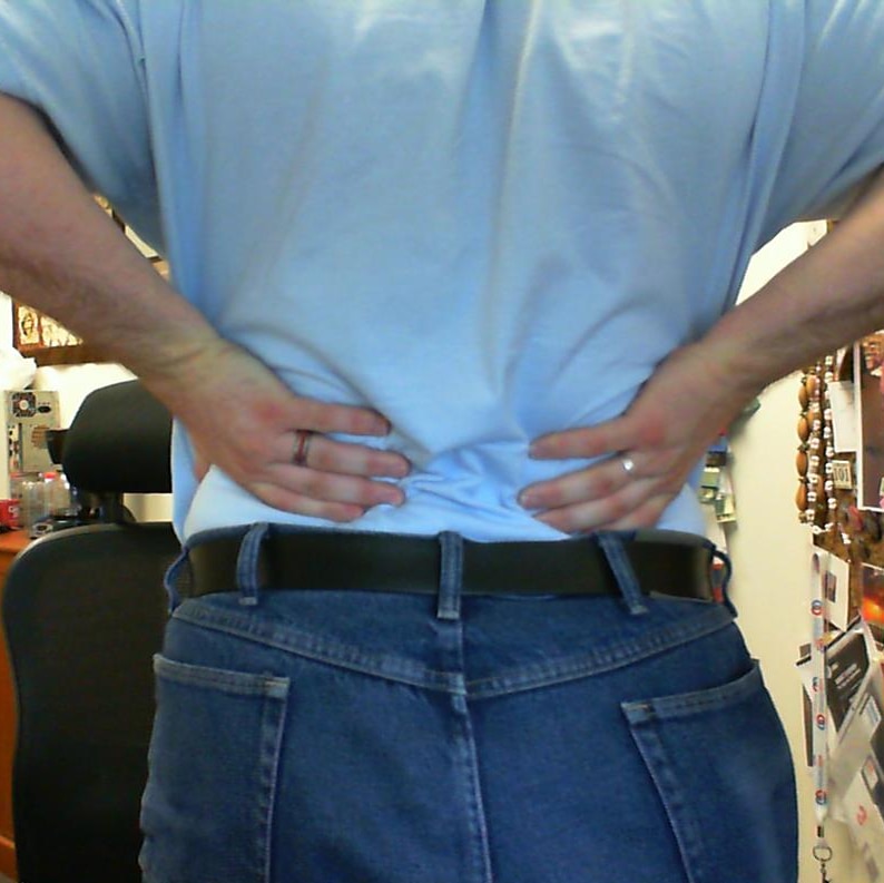 A photo of a person holding onto their back in response to back pain.