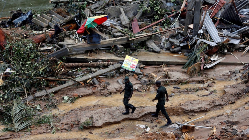 Sri Lankan army soldiers walk past the debris of houses at a landslide site during a rescue mission in Sri Lanka.