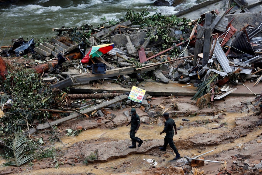 Sri Lankan army soldiers walk past the debris of houses at a landslide site during a rescue mission in Sri Lanka.