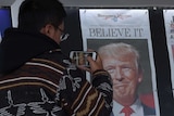 A Chinese man photographs the front pages of newspapers showing a Donald Trump election victory.